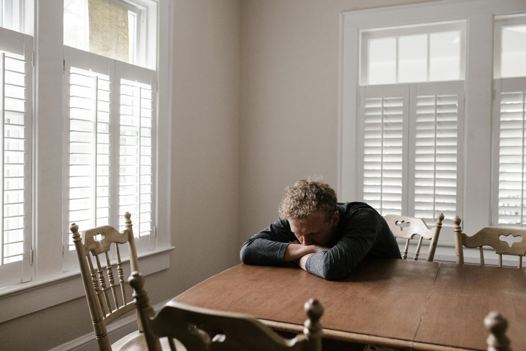Tired man with head down sitting at a table
