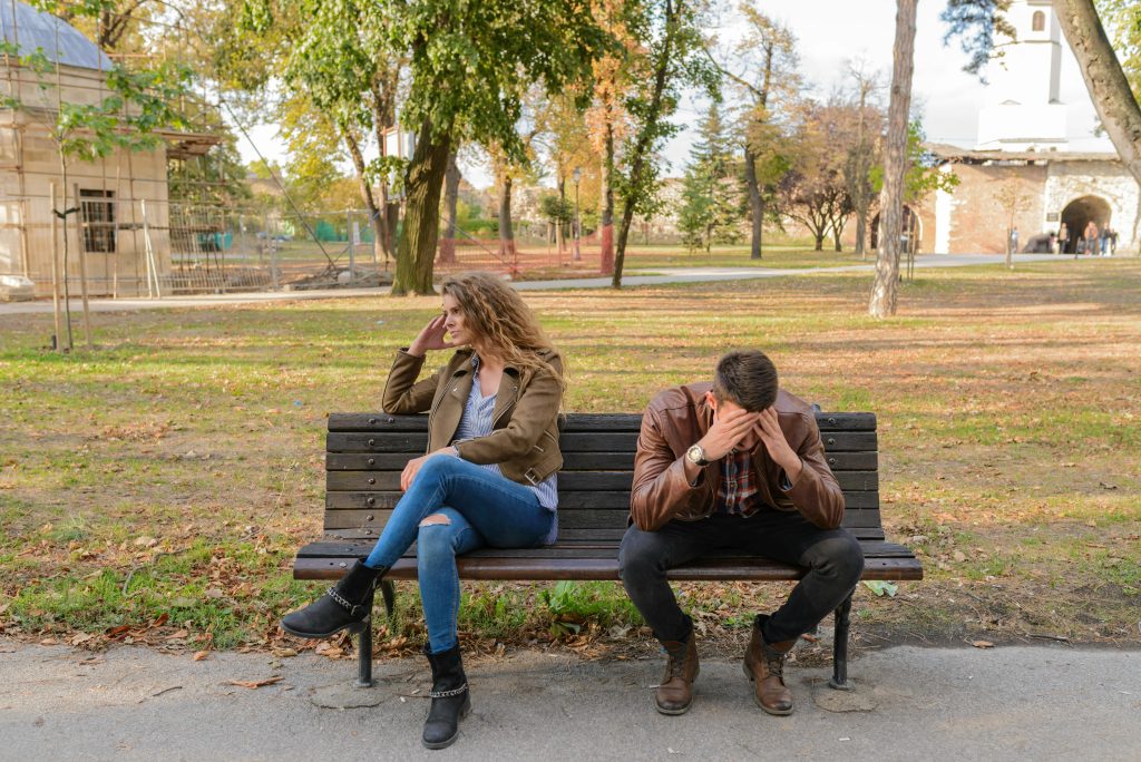 Two people sitting on bench looking stressed