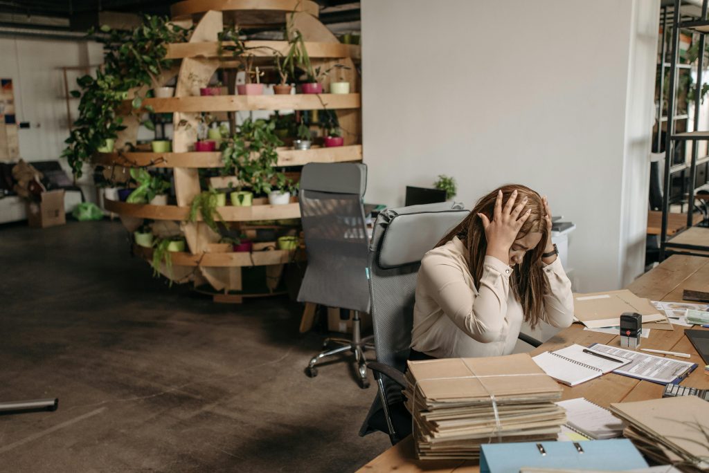 Woman holding her head at a desk