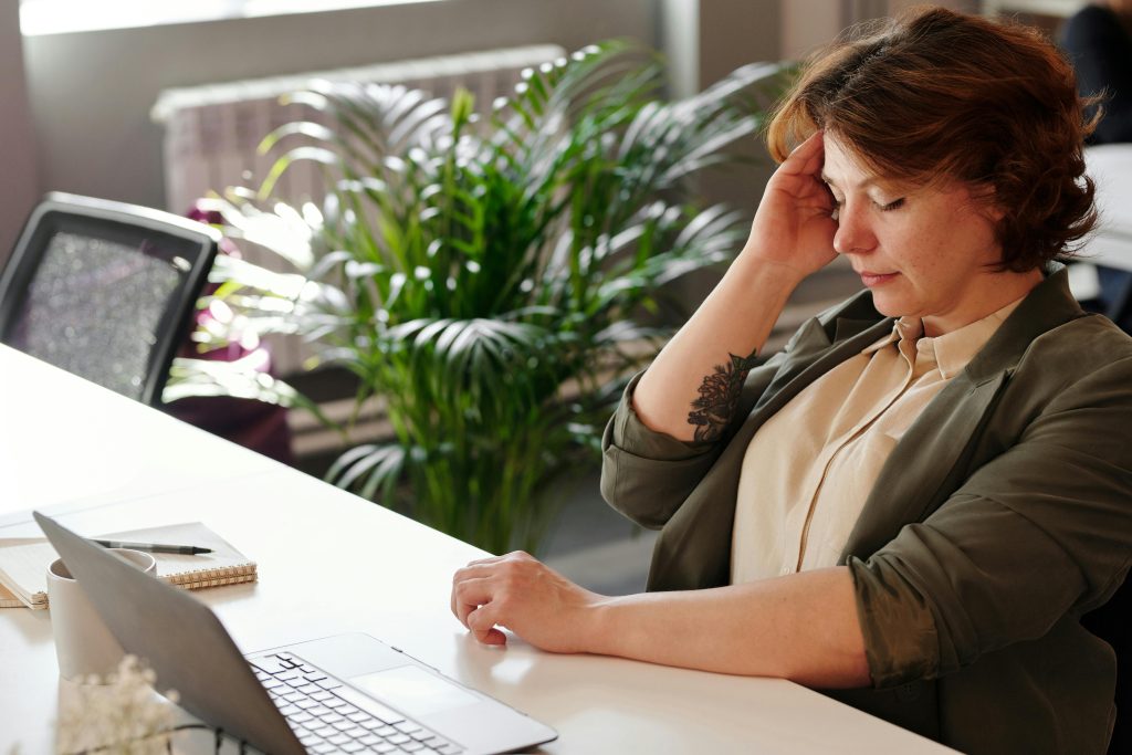 Woman sitting at a desk holding her head from a headache