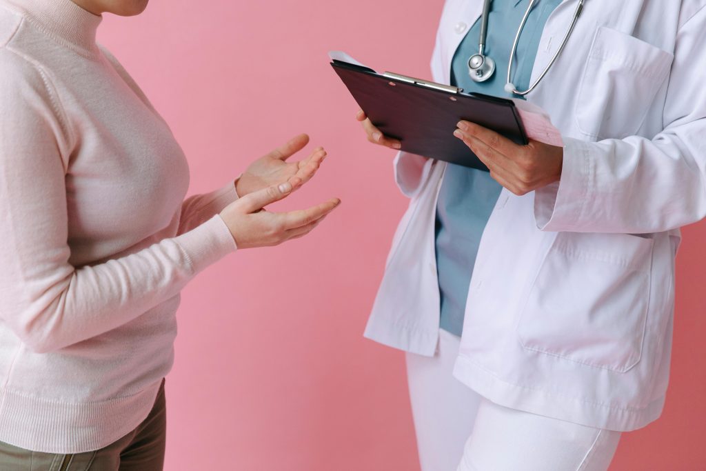 Woman talking to a doctor with a pink background