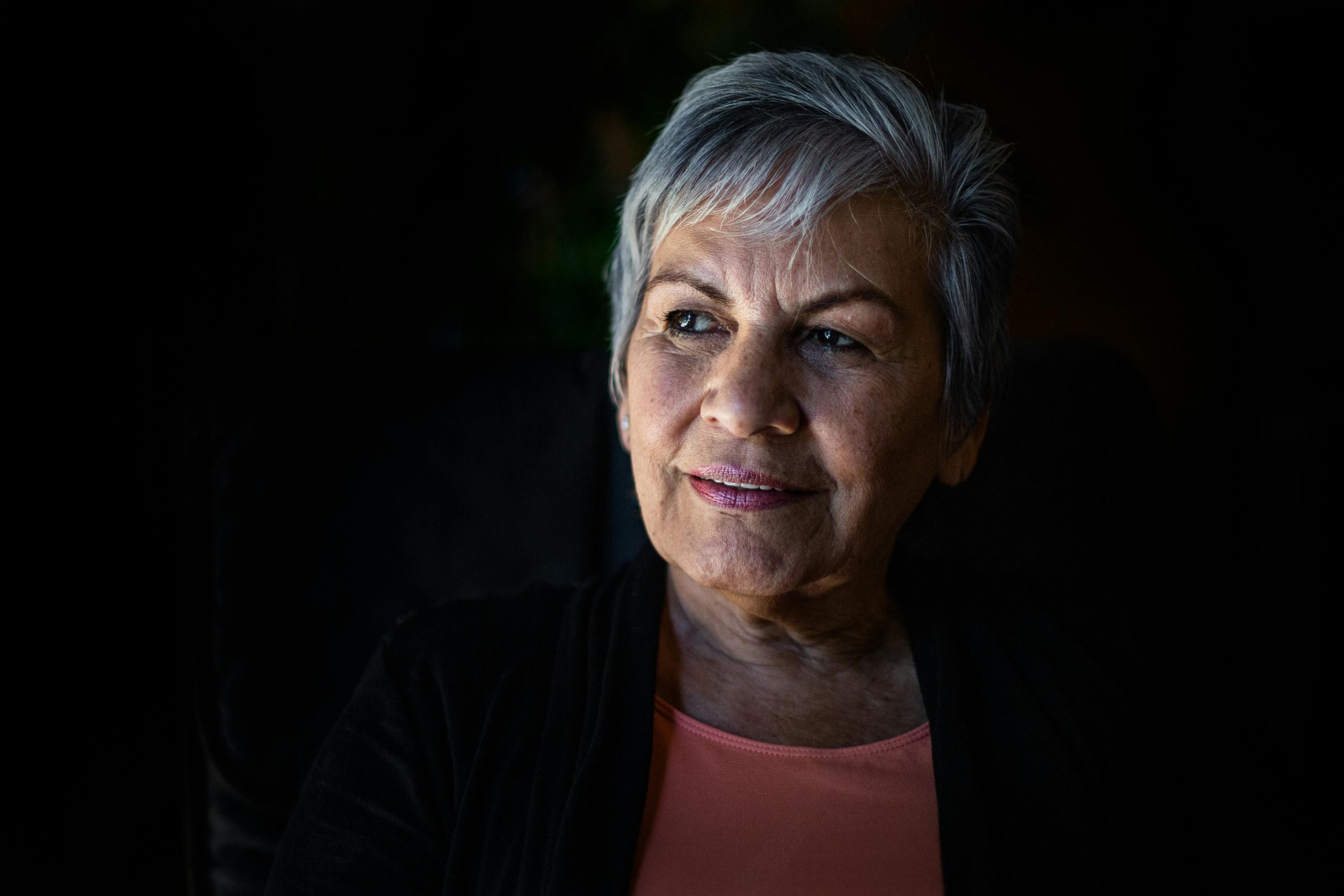 Older woman standing against a dark background