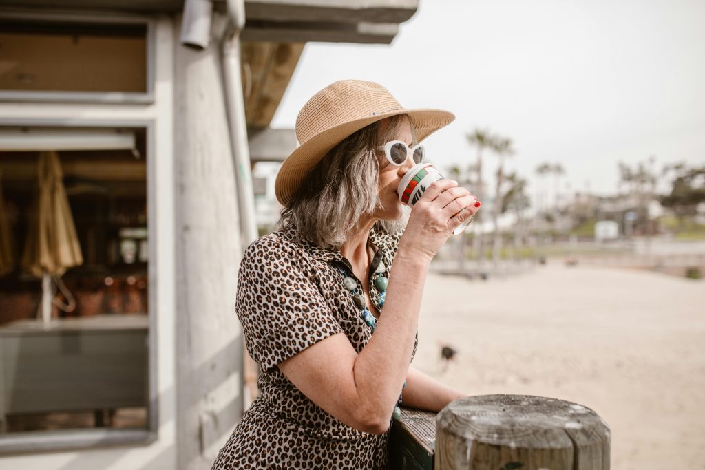 Older woman sipping coffee on a beach