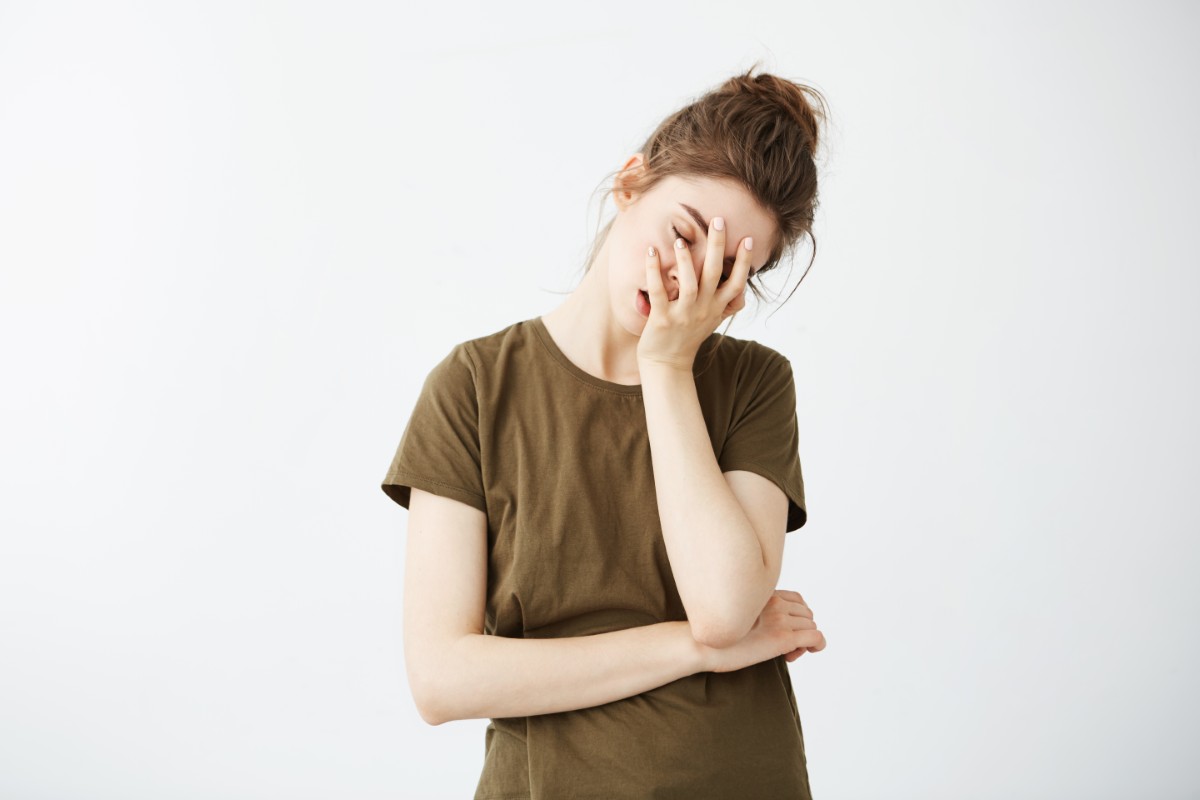 Portrait of displeased bored tired girl with bun over white background.
